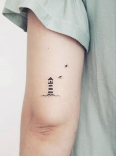 a small lighthouse tattoo on the arm