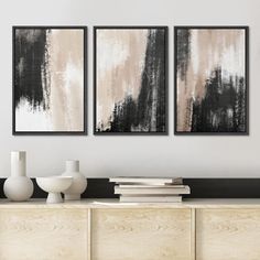 two black and white paintings hanging above a dresser