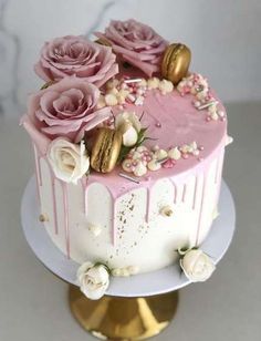 a cake with pink frosting and flowers on top is sitting on a gold plate