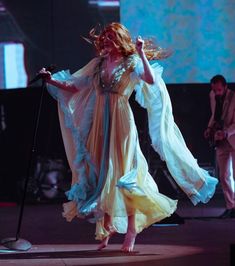 a woman is performing on stage with her hands in the air