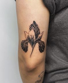 a black and white flower tattoo on the right arm by a woman's elbow