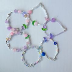 six bracelets with different colored beads and charms on white table top, closeup