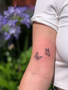 a woman's arm with two small butterflies on the left side of her arm