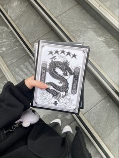 a person holding up a card with a dragon on it in front of some stairs