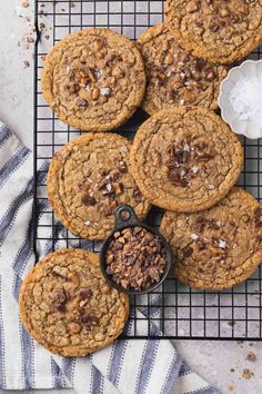 chocolate chip cookies cooling on a wire rack next to a bowl of powdered sugar