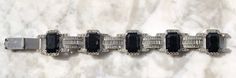 Beautiful Unsigned 1920's Deco Black Onyx Glass and Rhinestone Bracelet. FIVE Black Onyx emerald cut stones feature in this bracelet connected with 4 elongated Segments with baguettes and chatons creating fabulous deco patterns. This bracelet is very beautiful despite the fact that a few rhinestones are turning gray, the Rhodium finish on the back is still in very good vintage condition as in the photos. There is some wear to the edges of the segments which is consistent with age. Classic style Vintage Formal Bracelets With Stones, Formal Costume Jewelry Bracelet With Jewels, Formal Crystal Bracelet With Stones, Art Deco Gemstone Bracelet For Formal Occasions, Vintage Black Bracelet For Wedding, Antique Black Bracelets For Formal Occasions, Vintage Black Bracelet For Weddings, Luxury Art Deco Bracelet, Luxury Art Deco Gemstone Bracelets