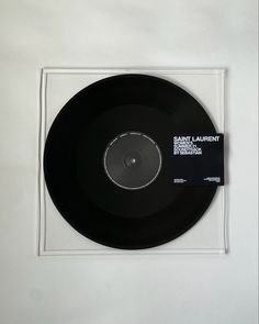 a black vinyl record sitting on top of a white table next to a plastic frame