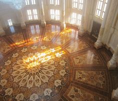 an ornately decorated floor in a large room with many windows and light coming through the window panes