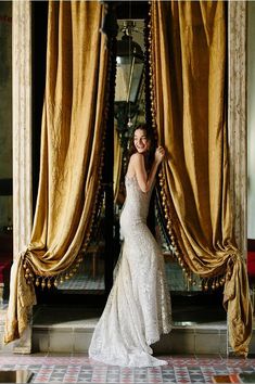 a woman standing in front of a gold curtain