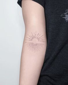 a woman's arm with a tattoo on it that has sunburst in the middle