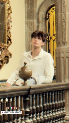 a man sitting on a balcony with a teapot in front of him and a mirror behind him