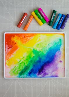 some crayons are sitting on a tray with paint