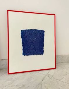 a blue and white square with red edges on a marble floor in front of a wall