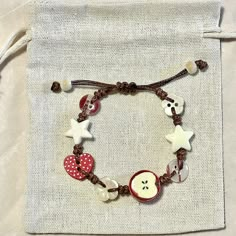 a bracelet with two hearts, an apple and a star on it is sitting in front of a bag