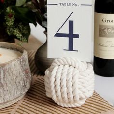 a table number is displayed next to a bottle of wine and a rope wrapped candle holder