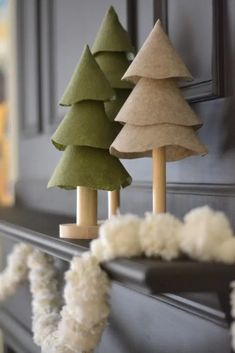 three wooden christmas trees on top of a mantle