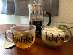 two mugs filled with liquid sitting on top of a wooden table