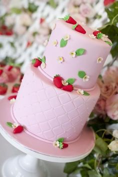 there is a pink cake with strawberries on it