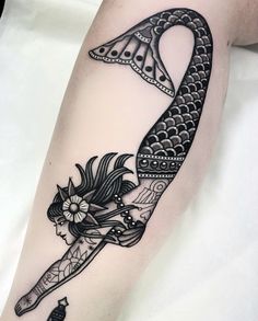 a woman's arm with a black and white tattoo design on it, holding a knife in the shape of a fish