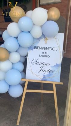 a blue and white balloon arch is in front of a sign that says benvenidos bauzo