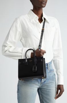 A compact Saint Laurent bag in smooth calfskin leather makes for a look that's as luxe as it is timeless. Featuring classic touches like the compression snap-straps that allow you to expand the capacity, as well as a leather-encased padlock and rolled top handles, the Sac de Jour is the last word in perennial style. Open top Top carry handles; adjustable shoulder strap Removable padlock with leather case; key fob snaps into interior of bag for storage Structured silhouette with flat base and pro