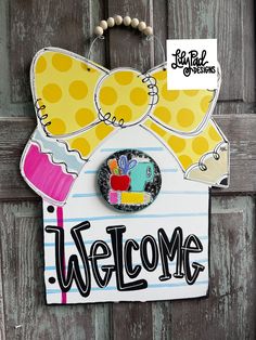 a welcome sign hanging from the side of a wooden door with a bow on it