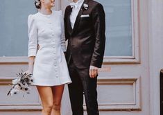 a man and woman standing next to each other in front of a door wearing formal attire