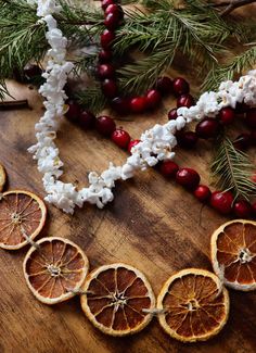 orange slices cut in half sitting on top of a wooden table next to flowers and berries