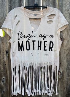 a white t - shirt that says tough as a mother on it with fringes