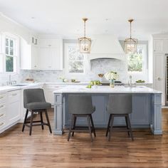 two gray chairs sit at an island in the middle of a kitchen