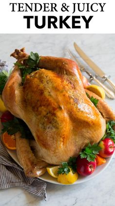 a roasted turkey on a platter with fruit and silverware