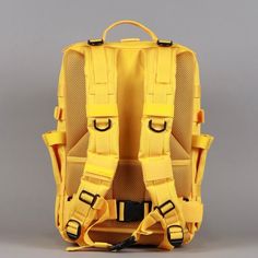 a yellow backpack with straps on the front and back sides, sitting against a gray background