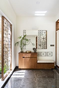 an entryway with a bench, mirror and potted plant on the sideboard