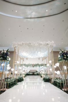 a white and gold wedding ceremony setup with flowers, greenery and chandeliers