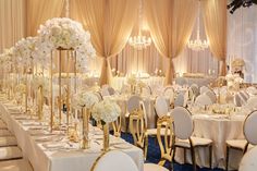 a banquet hall with tables and chairs covered in white flowers