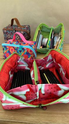 an open purse sitting on top of a wooden table next to other bags and pencils