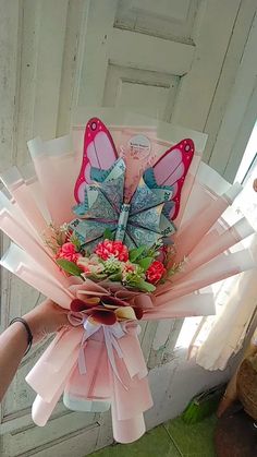 a person holding a bouquet of flowers with butterflies on it in front of a door