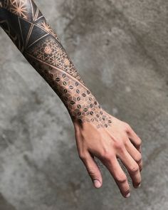 a man's arm with an intricate tattoo design on the left hand and wrist