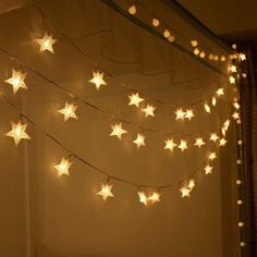 there is a string of stars hanging from the ceiling in front of a window with lights on it