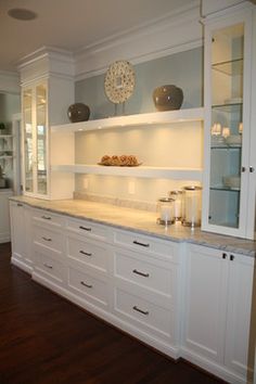 a kitchen with white cabinets and marble counter tops