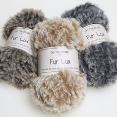 three balls of fur - like yarn sitting next to each other on a white surface