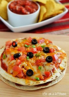 a tortilla with black olives, tomatoes and other toppings on it