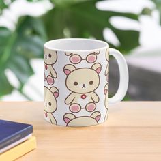 a coffee mug sitting on top of a wooden table next to a book and plant