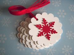 a red and white snowflake ornament hanging from a string on a blue background