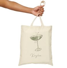 a hand holding a tote bag with a martini glass on it