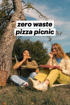 two women sitting under a tree eating pizza