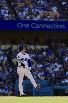 a baseball player holding a bat on top of a field in front of a crowd