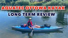 a woman sitting on top of a blue kayak in the middle of a lake