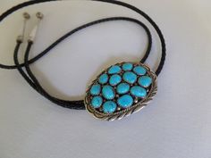 "This handsome bolo tie features turquoise set in sterling silver, by artist Marie B.  Clasp is 2\" long and 1.5\" wide.  The silver capped ends of the leather cord are 2\" long.  Marked STERLING." Southwestern Blue Bolo Tie For Gift, Southwestern Blue Bolo Ties As A Gift, Blue Lariat Bolo Tie For Gift, Elegant Blue Concho Jewelry, Elegant Blue Jewelry With Concho Detail, Handmade Turquoise Bolo Tie As A Gift, Handmade Turquoise Bolo Ties As Gifts, Handmade Silver Bolo Tie For Gift, Handmade Silver Bolo Tie As A Gift