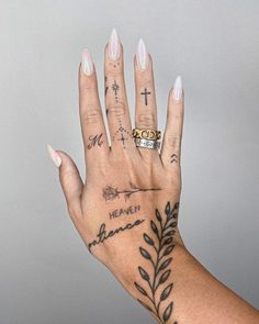 a woman's hand with tattoos and rings on it